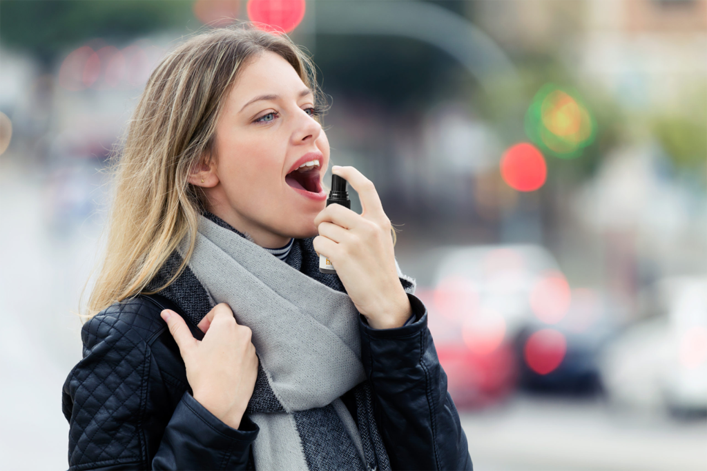 Woman in grey scarf using a CBD Oil Spray