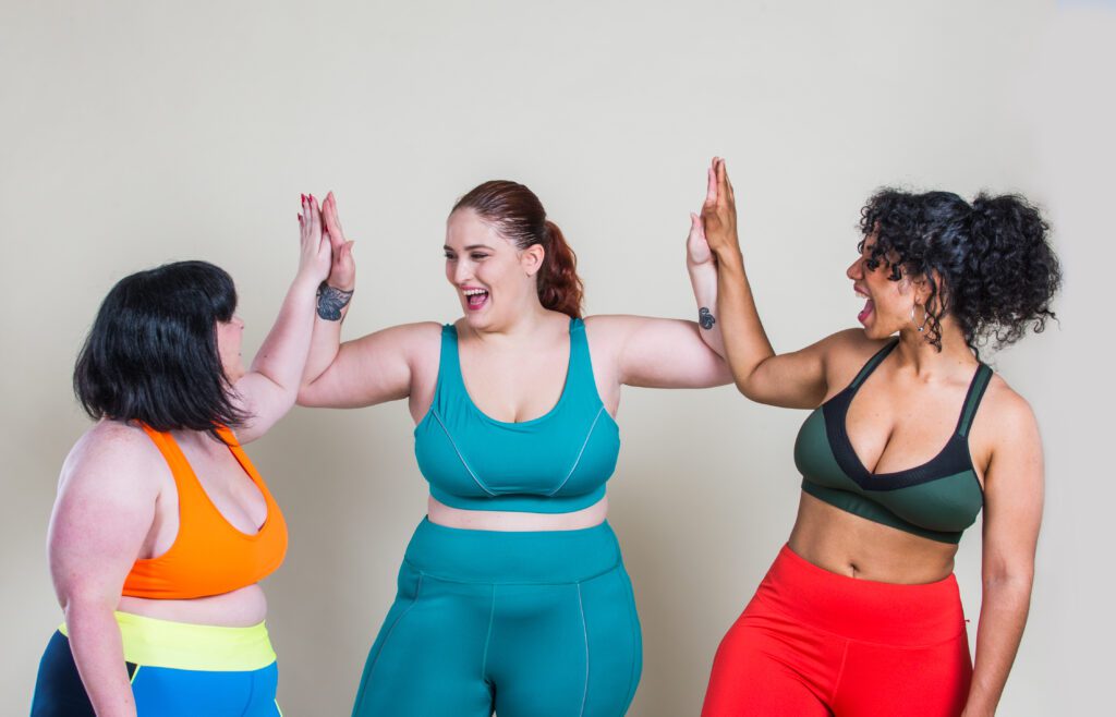 three women in workout clothes high-fiving each other